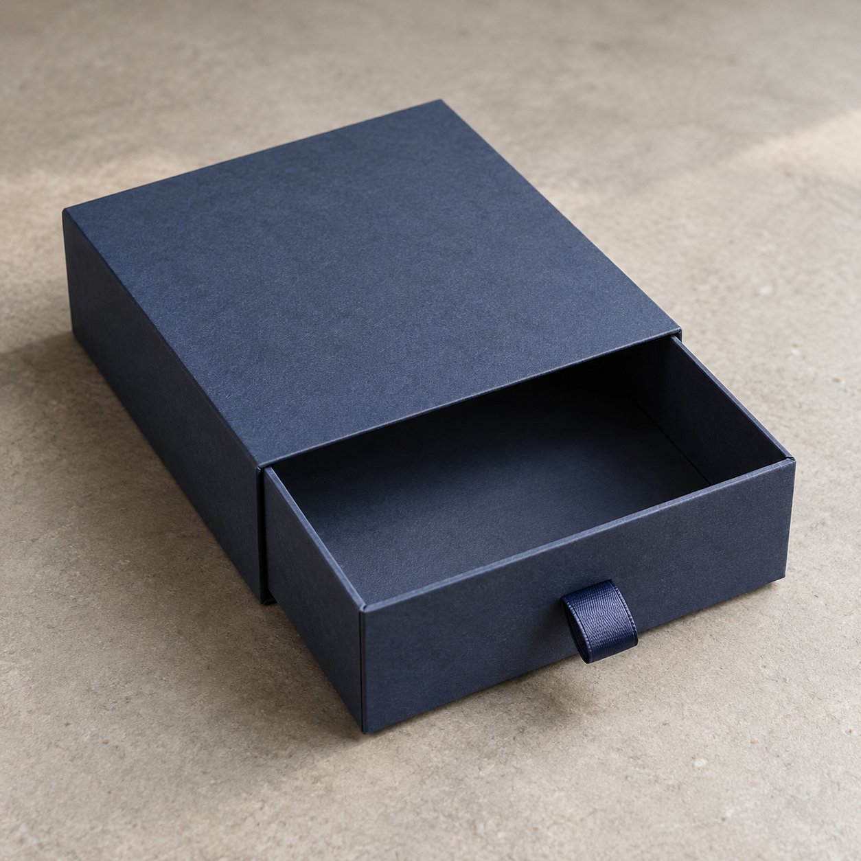Paper-wrapped rigid drawer box with a ribbon pull